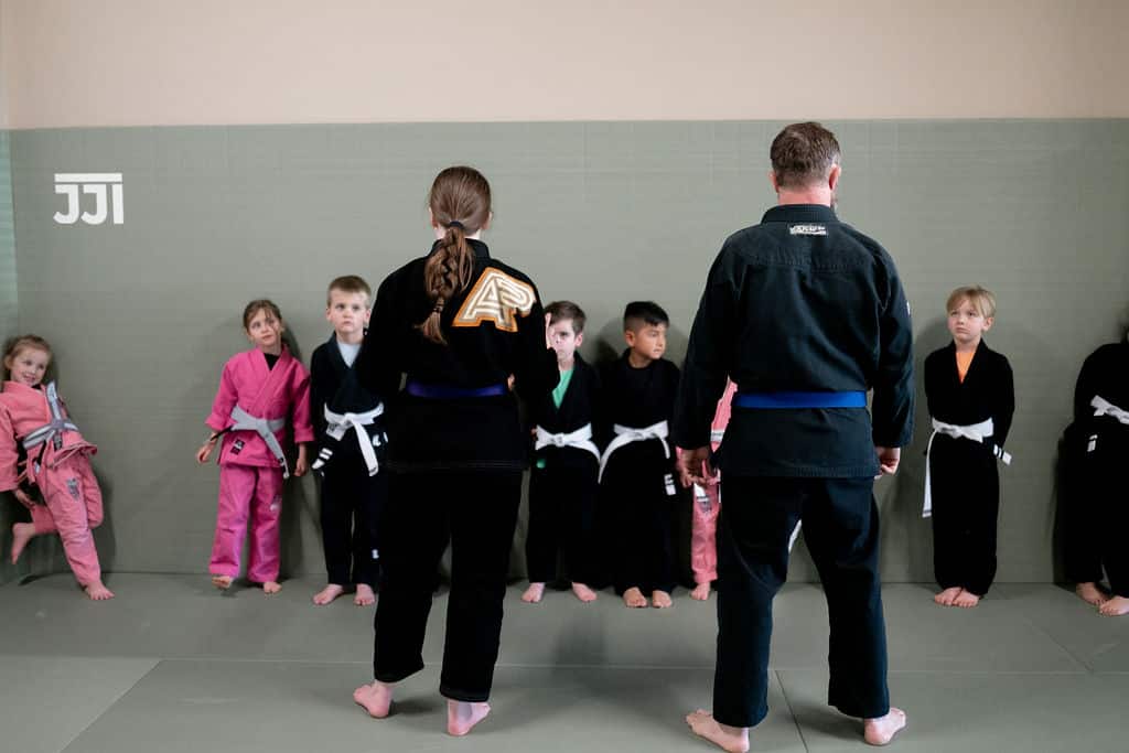 two Jiu Jitsu Institute instructors talking with young students lined up for jiu jitsu class
