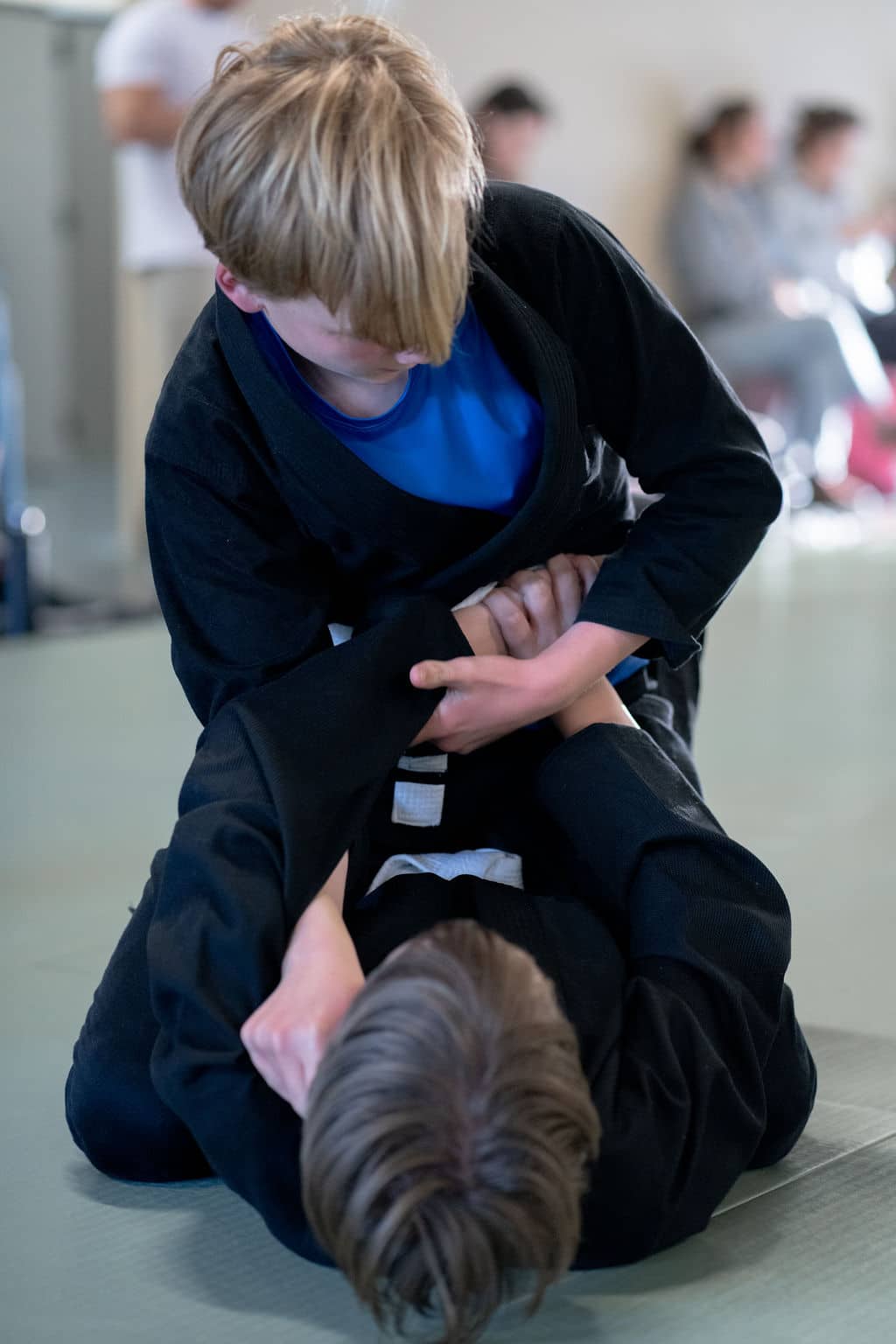 Two young Jiu Jitsu Institute students laying on mat sparring during class