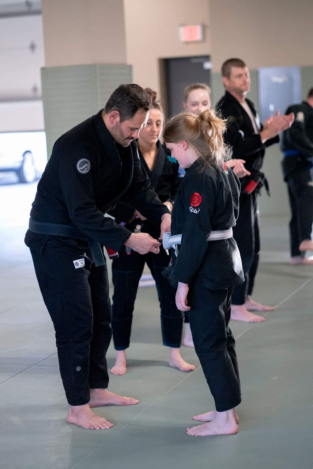 The Jiu Jitsu Institute instructor tying new belt color onto young student