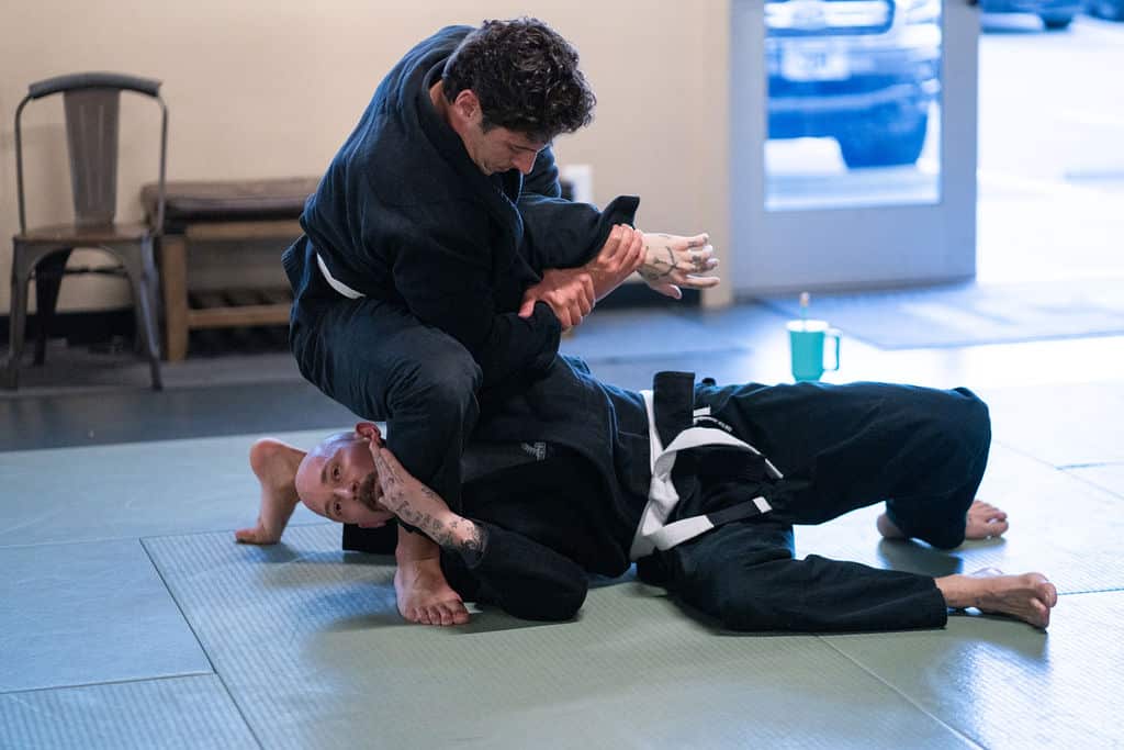 Two Jiu Jitsu Institute male adult students sparring in gym during class