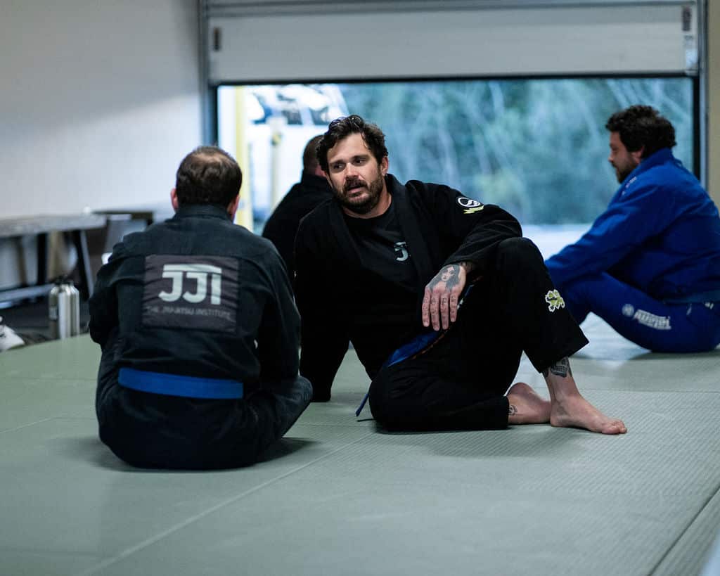 Two Jiu Jitsu Institute students sitting on mat talking after classes